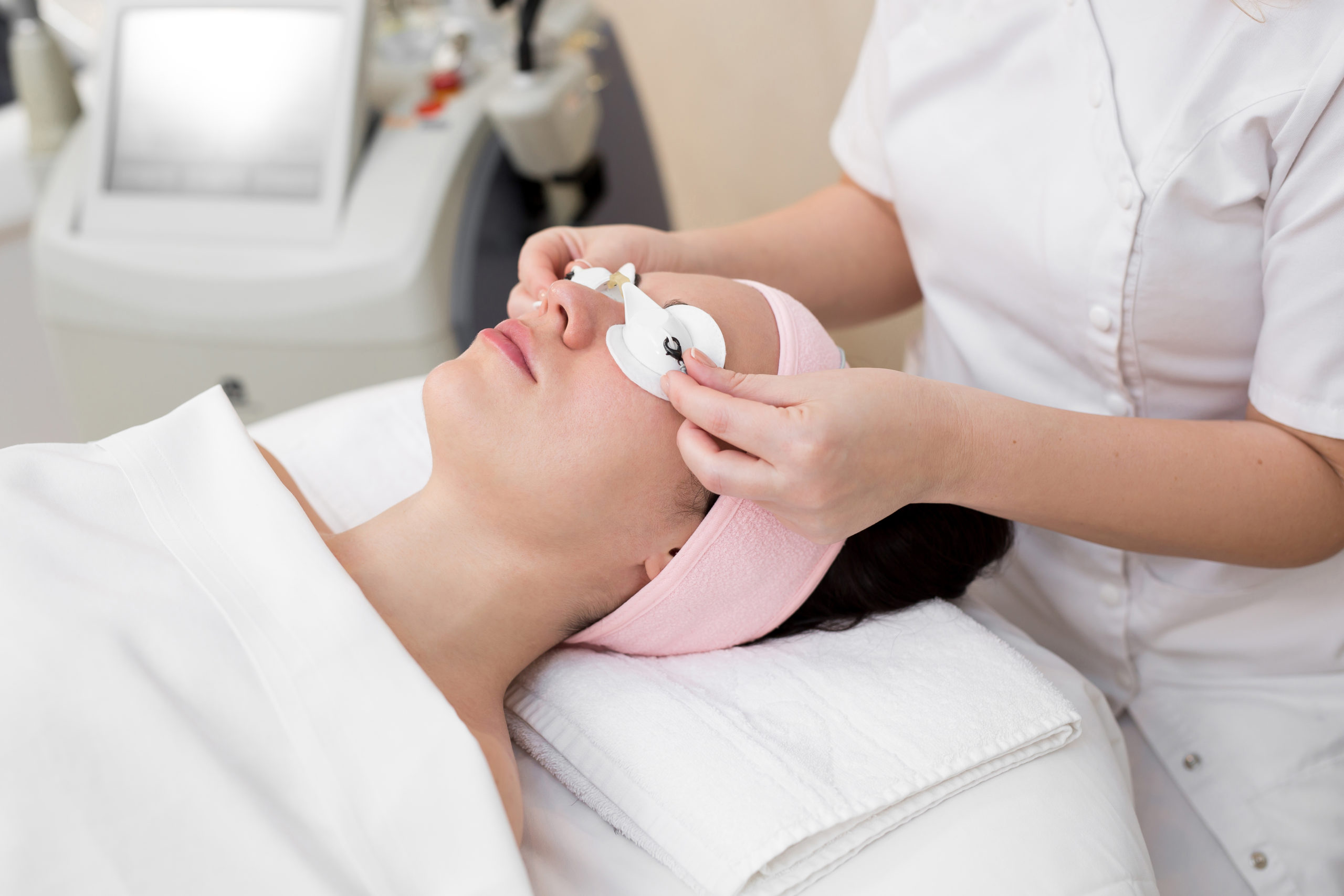 Close-up of a beautician dresses protective glasses from a girl's eyes after a cosmetic procedure. Process of radio wave lifting in the spa salon